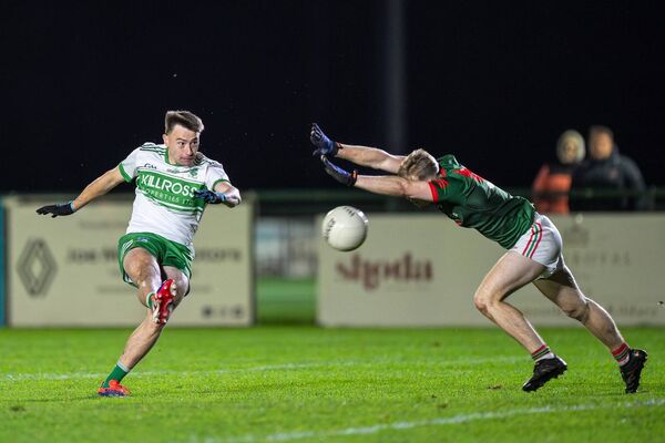 Paul Farrelly (Sallins) kicks a score despite the best efforts of Milltown's Cian Buckley.