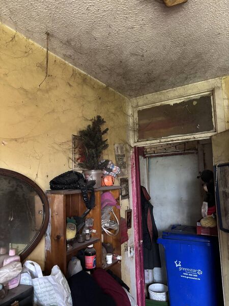 A bedroom in the Bickerdike’s home in poor condition with a bin in the hallway