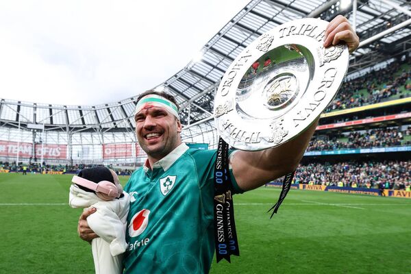 Tadhg Beirne celebrating at the Aviva Stadium with his daughter Penelope and the Triple Crown Trophy. 
