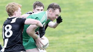 <p>Sarsfields midfielder Gavin Anderson tries to break through the tackles of two Maynooth defenders Photo: Sean Brilly</p>