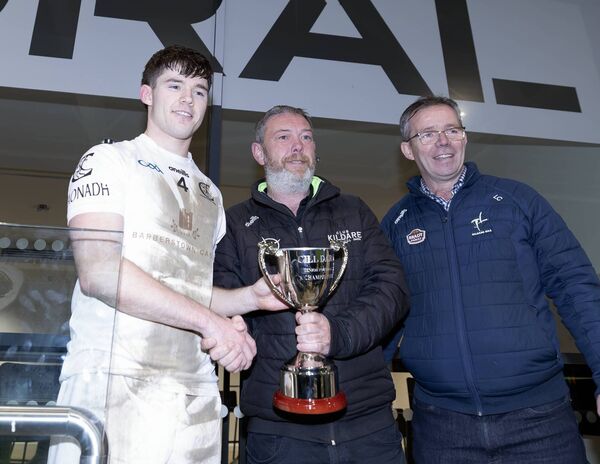 Dave Cahill and Larry Curtin of Kildare GAA present Clane captain Hugh Prendergast with the Senior 'A' Football Championship trophy Photo: Sean Brilly